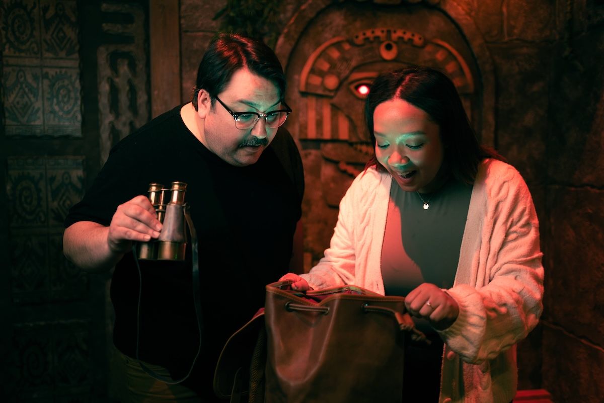 A man and woman looking inside a burlap bag with their faces illuminated