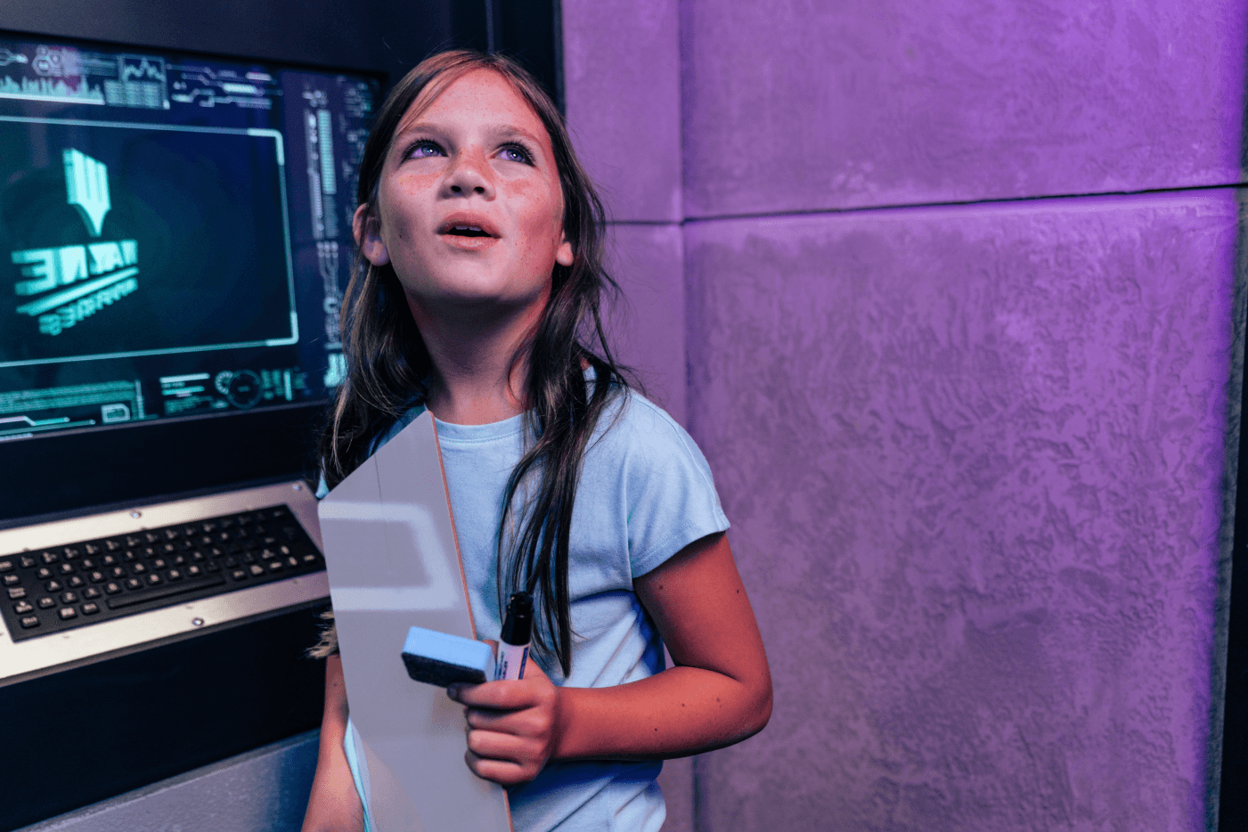 Child looking around in Batcave with keyboard behind them.