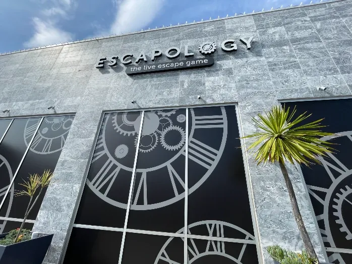 Escapology The live escape game sign on storefront with large clock outlines on windows